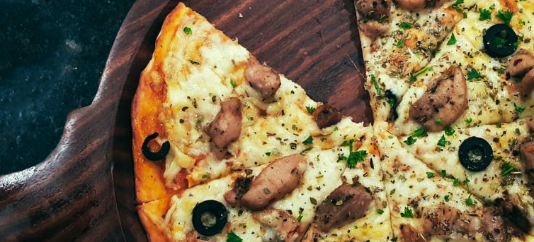 Olive and mushroom pizza over a wooden board.